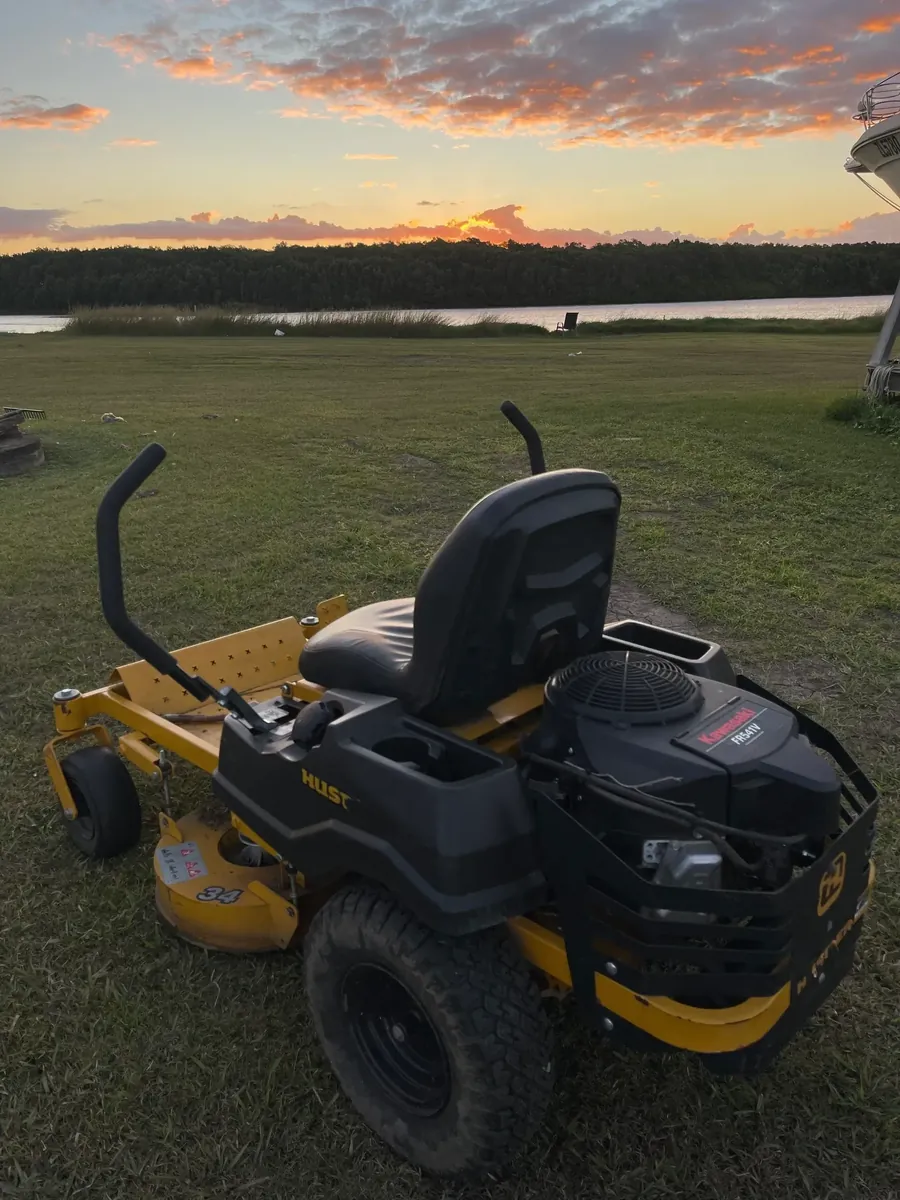 Ride-on mower on a riverside paddock at sunset — acreage mowing Northern Gold Coast